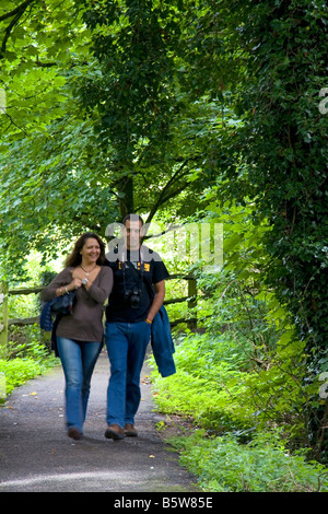 Paare, die einen von Bäumen gesäumten Weg in das Dorf von Bibury Gloucestershire-England Stockfoto