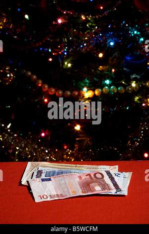 Haufen von Euro-Bargeld vor der Weihnachtsbaum Stockfoto