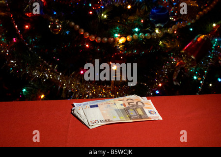 Haufen von Euro-Bargeld vor der Weihnachtsbaum Stockfoto