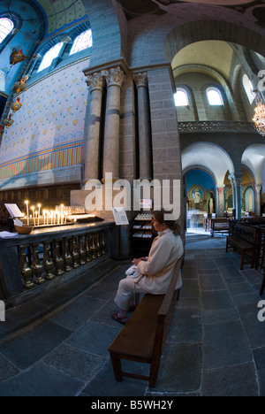 Eine Frau sitzt in stillem Gebet vor dem Altar, Kathedrale de Notre Dame du Puy Stockfoto