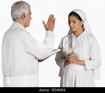 Nonne mit einem Priester ihre Sünden bekennen Stockfoto