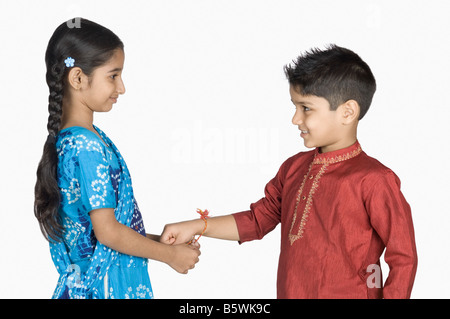 Seitenansicht eines Mädchens binden Rakhi am Handgelenk ihres Bruders Stockfoto