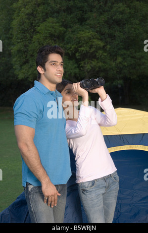 Frau, die durch ein Fernglas mit einem Mann, der neben ihr Stand Stockfoto