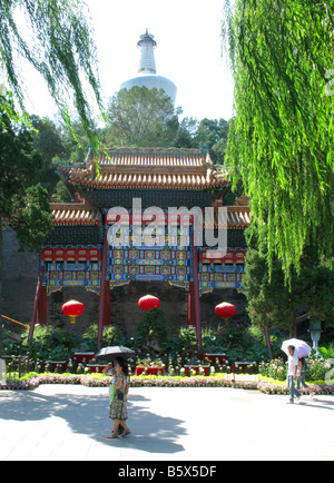 Zwei Personen mit Sonnenschirmen am Eingang der weißen Pagode auf Jade Inselchen in der Beihai-Park in Peking. Beijing China Asien Stockfoto