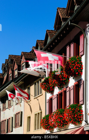 Flaggen werden auf die Häuser in einer typischen Schweizer Stadt im Nordwesten der Schweiz angezeigt. Stockfoto