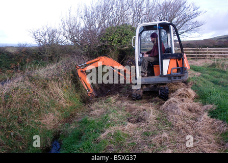 Simon Buttimore graben Graben mit einem Mini Bagger auf der Insel Man Stockfoto