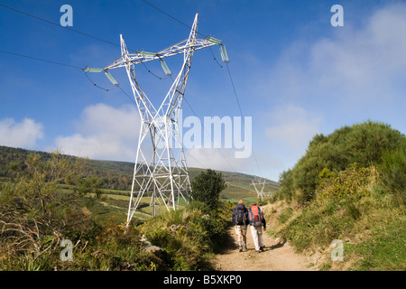 Ein paar Wanderungen unter Hochspannungsleitungen und Turm entlang des Camino de Santiago zwischen O Cebreiro und Triacastela, Galizien, Spanien. Stockfoto