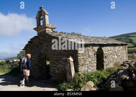 Ein Pilger besucht eine kleine steinerne Kapelle auf dem Jakobsweg zwischen O Cebreiro und Triacastela, Galizien, Spanien. Stockfoto