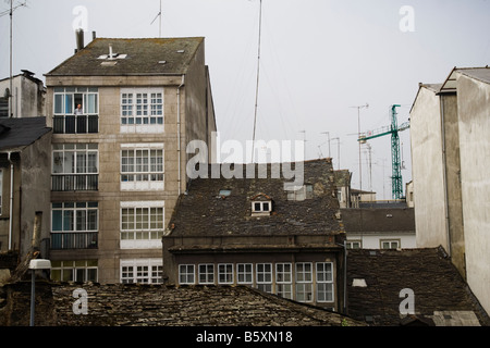 Ein Mann schaut aus dem Fenster seiner Wohnung in der obersten Etage eines Gebäudes in Lugo, Galizien, Spanien. Stockfoto