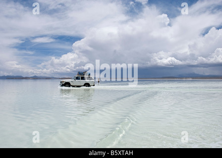 Ein 4wd kreuzt die überfluteten bolivianischen Salz-Ebenen Stockfoto