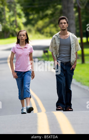 Ein junger Mann und eine Frau Fuß in der Mitte einer Landstraße. Teenager Straße Stand Familie ländlichen stehen keine Autos Stockfoto