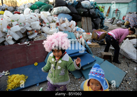 Ein kleines Mädchen mit Perücke aus dem Papierkorb in einer Recyclingstation in dongxiaokou Stadt im nördlichen Stadtrand Beijing, China Stockfoto