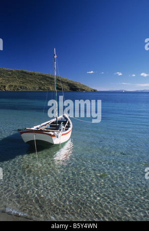 Segelboot in klarem, flachem Wasser in der Nähe der Küste mit flauschigem Sonnenlicht auf Kieselsteinen, Isla del Sol / Sonneninsel, Titicacasee, Bolivien Stockfoto