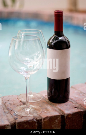 Eine Flasche Rotwein und zwei leere Gläser am Pool genügend Bewegungsfreiheit Kopie auf die leere Weinetikett Stockfoto