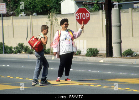 Crossing Guard stoppt Verkehr, so dass junge Straße sicher überqueren kann. Stockfoto