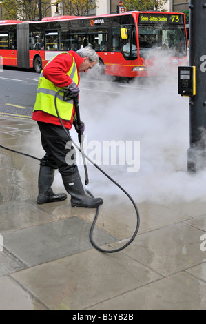 Oxford Street West End London Arbeiter-Warnjacke mit Hochdrucklanze Dampf-sauberes Kaugummi fiel auf Gehwege England UK Stockfoto