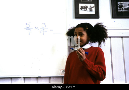 Kleine schwarze Schülerin an einem Whiteboard suchen besorgt. Stockfoto