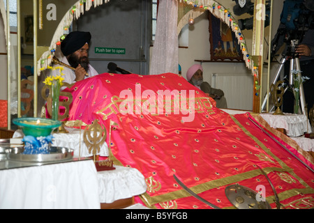 Ein Mann liest von Shri Guru Granth Sahib, Sikh Heiligen Texte im Inneren des Tempels in Freeman Straße, Grimsby, Lincolnshire, Großbritannien Stockfoto