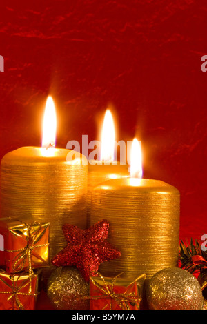 Drei brennende Kerzen in einem Weihnachts-Ambiente mit Saisondekorationen Stockfoto