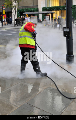 Gut sichtbare Arbeitsweste mit Hochdruckreiniger-Dampfreiniger-Lanze zum Entfernen von Kaugummi vom Straßenbelag in Oxford Street West End London, England Stockfoto