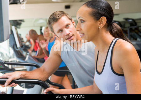 Personaltrainer, die Förderung der Frau mit Laufband im Fitnessstudio Stockfoto