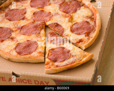 Peperoni-Pizza in einer Take Away Box mit einer geschnittenen Scheibe Stockfoto