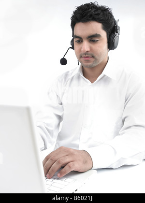 asiatischer Mann auf seinem Laptop mit seinen Kopfhörern arbeiten Stockfoto