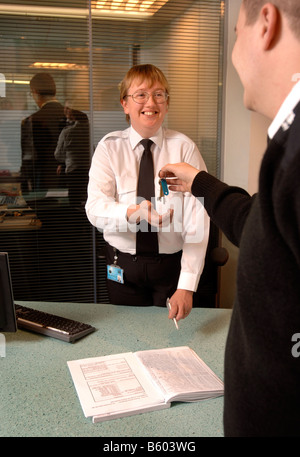 EIN WACHMANN AUF PATROUILLE PÄSSE-TASTEN, UM EINE FRONT DESK SECURITY OFFICER AT A BUSINESS RÄUMLICHKEITEN UK Stockfoto