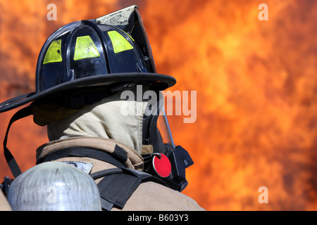 Profil eines Feuerwehrmannes vor ein loderndes Feuer-Inferno auf der Suche nach Anleitungen Stockfoto