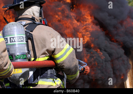 Feuerwehrleute vor einem lodernden Feuer Inferno die Wasser-Schlauchleitung Verwendung vorbereiten Stockfoto