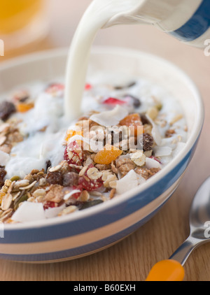 Gießen Sie Milch in eine Schüssel mit Müsli Stockfoto