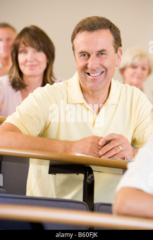Mann, sitzend in Erwachsenen Klasse mit Studenten im Hintergrund (Tiefenschärfe) Stockfoto