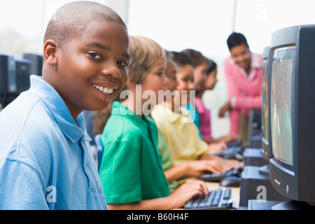 Sechs Kinder am Computer-Terminals mit Lehrer im Hintergrund (Schärfentiefe-Bereich/High-Key) Stockfoto