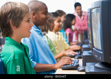 Sechs Kinder am Computer-Terminals mit Lehrer im Hintergrund (Schärfentiefe-Bereich/High-Key) Stockfoto