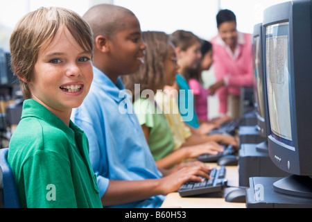 Sechs Kinder am Computer-Terminals mit Lehrer im Hintergrund (Schärfentiefe-Bereich/High-Key) Stockfoto