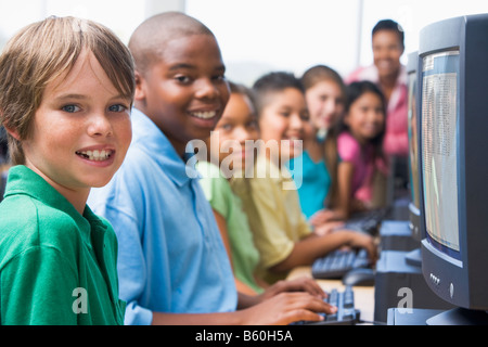 Sechs Kinder am Computer-Terminals mit Lehrer im Hintergrund (Schärfentiefe-Bereich/High-Key) Stockfoto