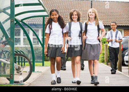 Drei Schüler verlassen die Schule mit anderen Studenten im Hintergrund Stockfoto