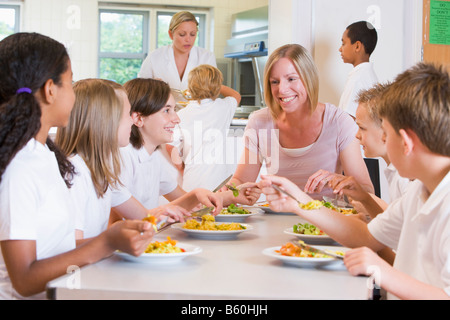 Studenten, die an Cafeteria Tisch essen mit Lehrer Stockfoto