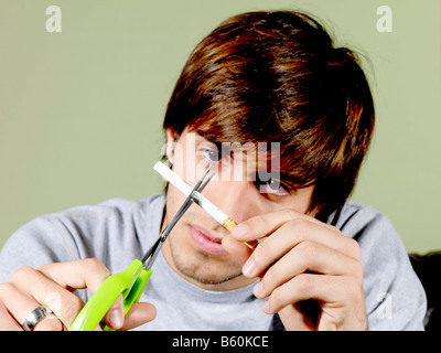 Junger Mann zerschneiden eine Zigarette Modell veröffentlicht Stockfoto