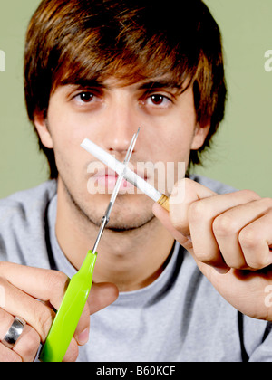 Junger Mann zerschneiden eine Zigarette Modell veröffentlicht Stockfoto