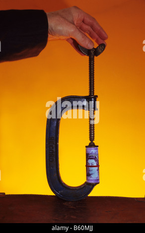 Hand mit Zange mit UK Sterling zwanzig Pfund-Noten Stockfoto