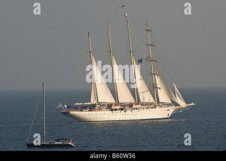 Ein großes Segelboot verläuft vor einem griechischen Dorf auf einer griechischen Insel Stockfoto