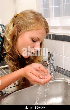 Junge Frau Trinkwasser aus dem Wasserhahn Stockfoto