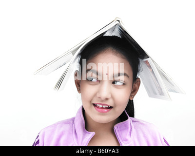 asiatische Mädchen indischer Herkunft mit einem Buch auf dem Kopf Stockfoto