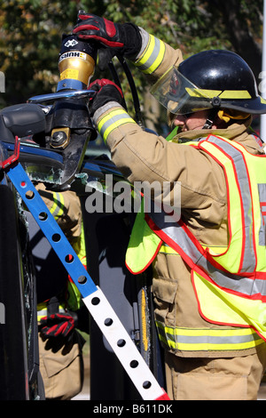 Feuerwehrmann hat das Backen des Lebens Bergung Werkzeug benutzt, um durch eine Stütze eines Autos zu schneiden, die über gerollt hat Stockfoto