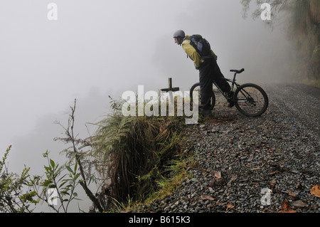 Denkmal zu überqueren, ein Mountainbiker auf der Deathroad Blick besorgt über einen Damm, Yungas, La Paz, Bolivien, Südamerika Stockfoto