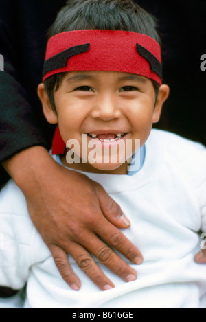 Portrait eines Happy Young Native American Heiltsuk indischen Jungen mit Vorderzähne fehlen und trägt ein rotes Stirnband Stockfoto