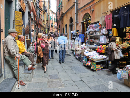 Zwei ältere Männer beobachten einen Souvenir-Shop in einer schmalen Gasse in Vernazzo, Ligurien, Cinque Terre, Italien, Europa Stockfoto