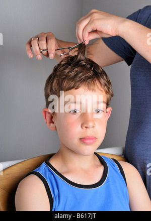 Neun Jahre alten Jungen, seine Haare mit einer Schere schneiden Stockfoto