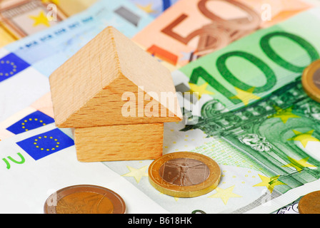 Ein kleines Haus am Euro-Banknoten, symbolisches Bild für Eigenheim finanzieren Stockfoto